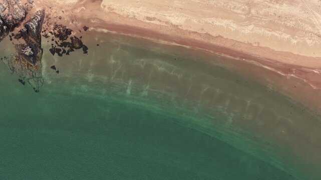 Drone flight over a Beach on the west coast of Scotland. Top down view showing clear blue water, golden sands and lush green vegetation. Taken at Firemore beach near Poolewe.