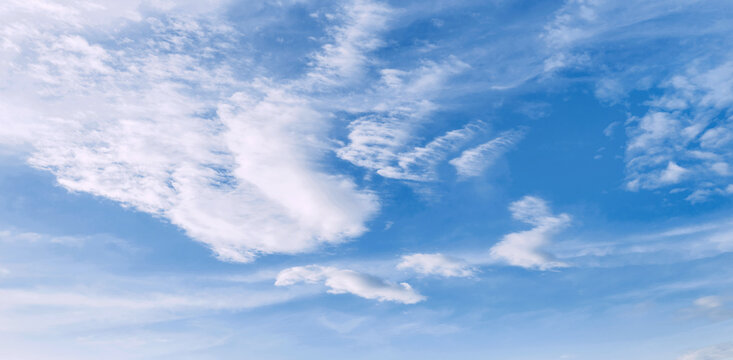 Soft clouds drift across a vast, serene blue s