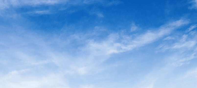 Soft clouds drift gently across a vast blue sky