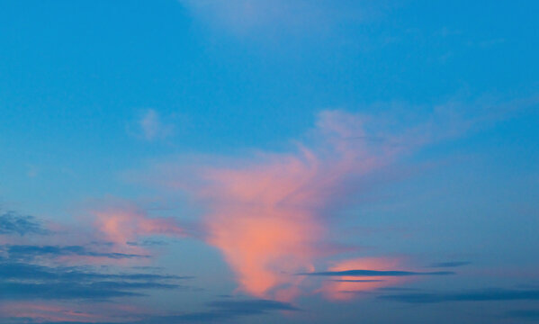 Soft pink clouds drift against a deep blue sky
