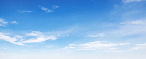 Clear blue sky with wispy white clouds drifting gently