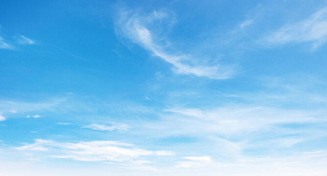 Clear blue sky with soft, wispy clouds