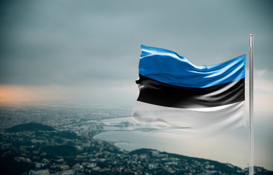 Estonia flag waving over a coastal city under dramatic cloudy sky, realistic fabric motion, aerial seaside landscape background. Estonia national flag for independence day.