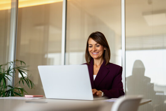40s businesswoman using laptop computer, typing at office desk. 40 years old business woman works as accountant analyst manager, checking company email, forecasting quarterly budget. Copy space.