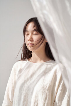Peaceful young woman with closed eyes in soft linen top for wellness background and mindful lifestyle