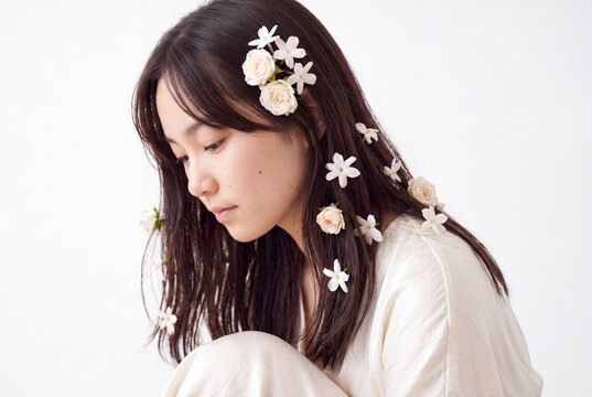 Serene side profile portrait of a woman with white flowers in her hair for editorial beauty background and wellness banner design
