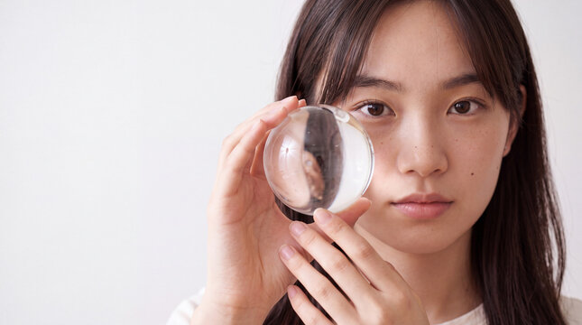 Young woman holding a clear glass sphere frontal portrait for minimalist background and product display banner design