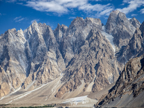 Aerial view of the jagged Passu Cones in the Karakoram mountain range, featuring sharp granite peaks, steep rocky slopes, and glacial debris in Gilgit-Baltistan, Pakistan.