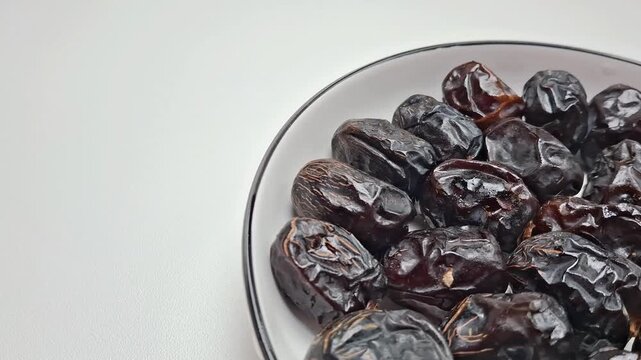 Dried date fruit in white bowl, organic sweet dates on ceramic plate, healthy middle eastern snack on white background