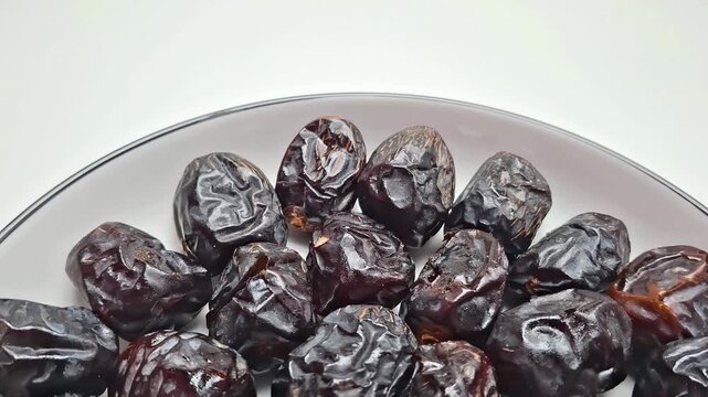Dried date fruit on ceramic plate, sweet organic dates for Ramadan, healthy middle eastern snack on white background