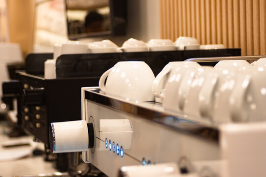 Professional espresso machine featuring clean white ceramic cups warming on top, ready for serving hot coffee in a busy cafe or elegant coffee bar setting
