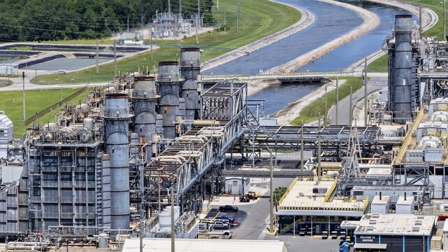 Aerial view of the FPL Sanford Power Plant with its industrial structures, cooling towers, and complex piping systems situated near a canal in DeBary, Florida, United States.