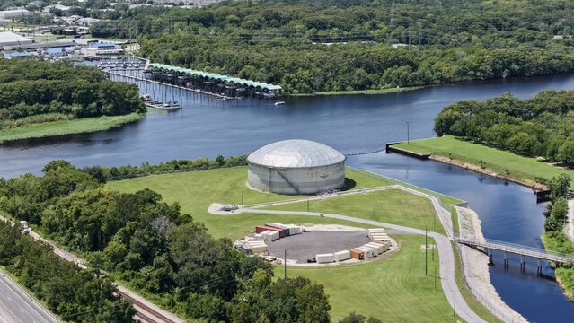 Aerial view of the FPL Sanford Power Plant featuring its prominent dome structure, surrounded by lush green lawns, the St. Johns River, and a nearby marina in DeBary, Florida, United States.