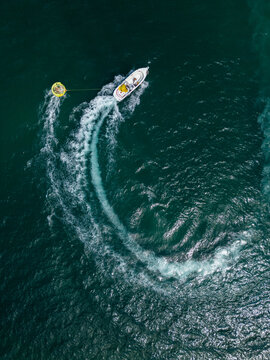 Aerial View of Speedboat Towing Inflatable Tube on Deep Blue Sea