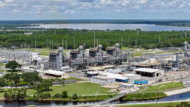 Aerial view of the FPL Sanford Power Plant, showing industrial infrastructure, power units, electrical substations, and green landscape near a lake in DeBary, Florida, United States.
