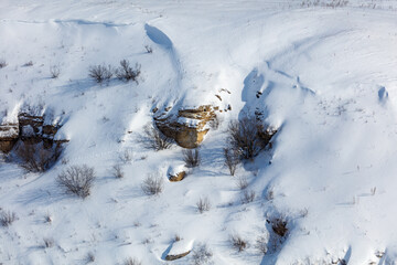 Naklejka premium Snow blankets rugged terrain with exposed rock outcrops