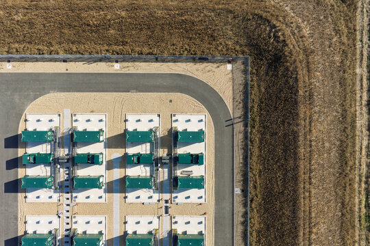 Aerial view of green industrial containers arranged in rows on a concrete pad within a fenced facility in the United Kingdom.