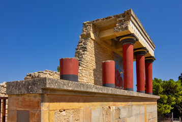 Naklejka premium A reconstructed section of the Palace of Knossos on Crete, Greece, featuring the characteristic red Minoan columns, decorated architectural elements and a colorful bull fresco.