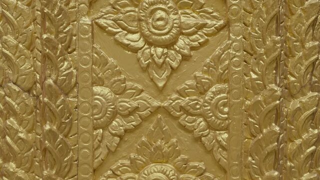 Golden texture inside a serene temple hall. High-detail 4K B-roll shot showing Thai Buddhist culture, religion, and spiritual art.