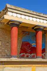Naklejka premium A reconstructed section of the Palace of Knossos on Crete, Greece, featuring the characteristic red Minoan columns, decorated architectural elements and a colorful bull fresco.