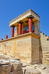 Naklejka premium A reconstructed section of the Palace of Knossos on Crete, Greece, featuring the characteristic red Minoan columns, decorated architectural elements and a colorful bull fresco.
