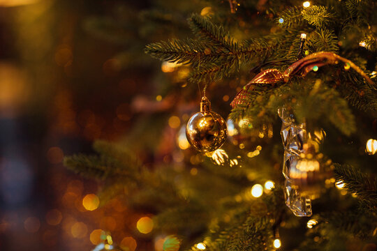 Close-up of a beautifully decorated Christmas tree with golden ornaments and twinkling lights, creating a festive atmosphere during the holiday season