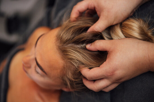 Female receiving relaxing scalp massage in a serene spa environment, showcasing hands gently working through hair, promoting wellness and tranquility for self-care experience