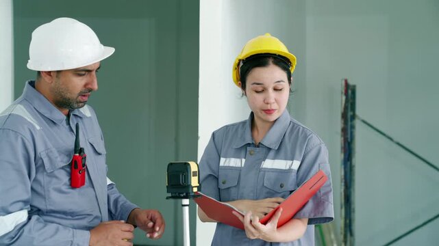 Two construction engineers inspecting building interior with laser level