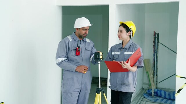 Two construction engineers inspecting building interior with laser level