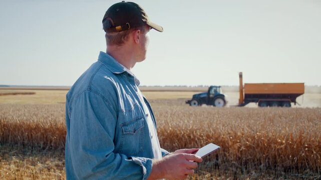 Agronomist with digital tablet controls harvester in wheat field