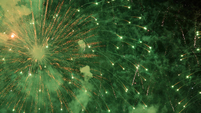 Vibrant green fireworks exploding with bright sparkles and smoke trail during New Year celebration, holiday festival event, independence day, annual party show, and pyrotechnic display at night