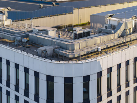 Aerial view of a modern office building rooftop featuring ventilation ducts, HVAC units, and industrial architecture in the late afternoon light in Krakow, Lesser Poland Voivode, Poland.