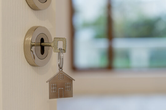Open door to a new home with key and home shaped keychain. Mortgage, investment, real estate, property and new home concept