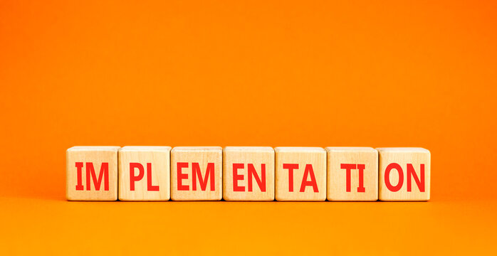 Implementation word symbol. Concept word Implementation on beautiful wooden blocks. Beautiful orange table orange background. Business implementation word concept. Copy space.