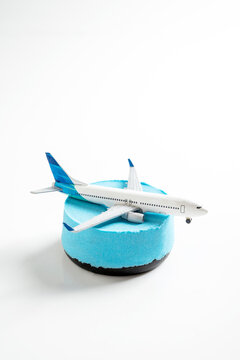 Miniature toy airplane resting on a light blue cylindrical block, isolated on a white background. Concept of travel or transportation