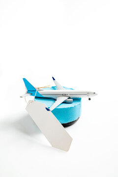 Toy airplane on a blue base with a blank price tag, representing cheap flights and travel promotions on a white background. Mockup or Copyspace
