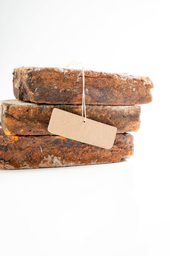 Three stacked rustic, weathered bricks with a blank brown paper label, isolated on a white background. Mockup or Copyspace