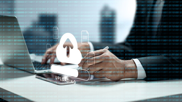 Businessman using a tablet to upload data to cloud storage, featuring a digital cloud icon and binary code background. Concept of cloud computing storage and digital storage technology