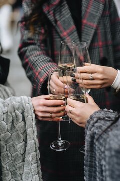 Young women holding champagne glasses outdoors at a party. Close-up photo.