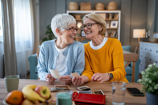 Senior women friends reminiscing old memories with photographs