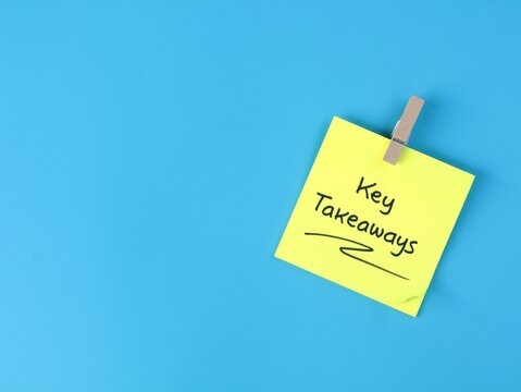 Key takeaways handwritten text on yellow adhesive note attached with wooden clothespin clip on vibrant blue paper background. Business summary concept, key points, reminder note with copy space