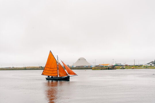 Galway Harbour and coastline with a traditional Galway Hooker sailing boat with a distinctive red sail, reflecting the maritime heritage of Galway, Ireland - Galway, Ireland - 31 August 2026.