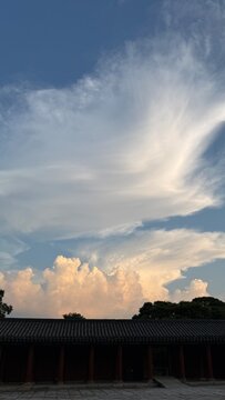 Dramatic vertical cloudscape with glowing sunset clouds over traditional Korean palace roof
