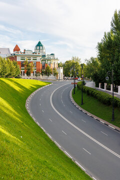 Curved empty road beside green park slope in Samara, Russia.