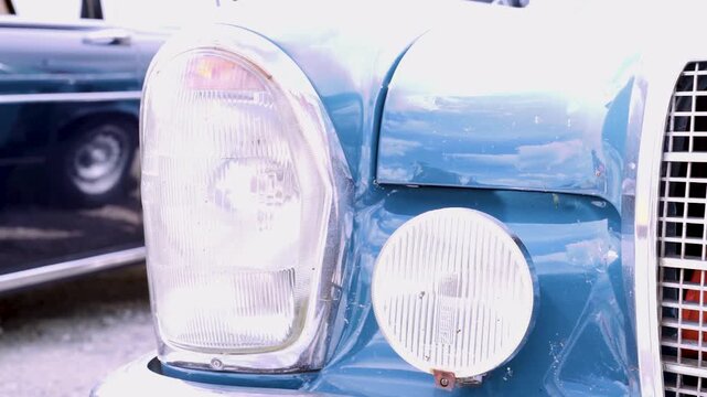Nahaufnahme der Scheinwerfer eines blauen Oldtimers