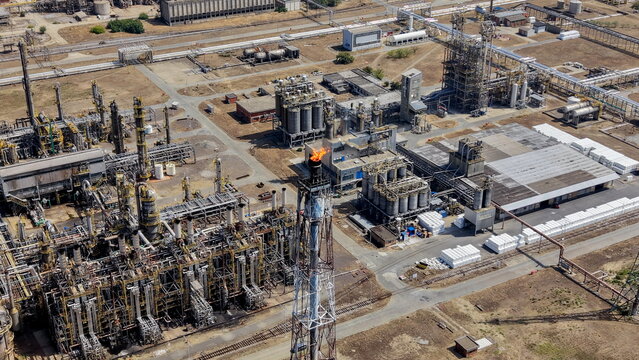 Aerial view of the petrochemicals industry complex featuring a flare stack with a burning flame, pipes, storage tanks, and industrial infrastructure in Pancevo, Serbia.