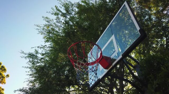 Low angle shot of basketball hoop in park setting during sunny day.