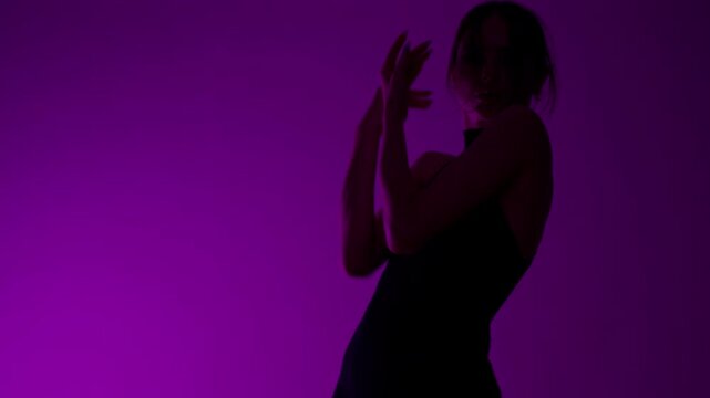 Graceful woman in silhouette dancing contemporary jazz funk in a studio with purple lighting