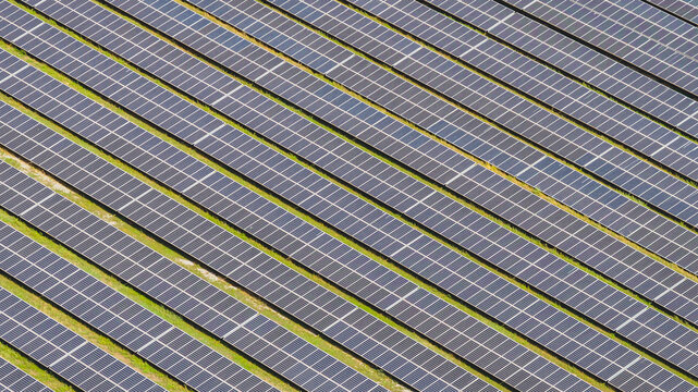 Aerial view of repeating rows of photovoltaic solar panels forming a geometric pattern across a large renewable energy installation in Le Pouzin, Auvergne-Rhone-Alpes, France.