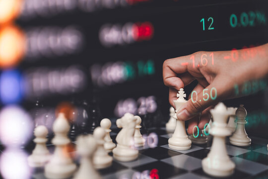 Businessman hand moving a chess king double exposed with glowing stock market numbers and data